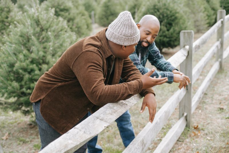 Padre e hijo adolescente apoyados en una valla manteniendo una conversación